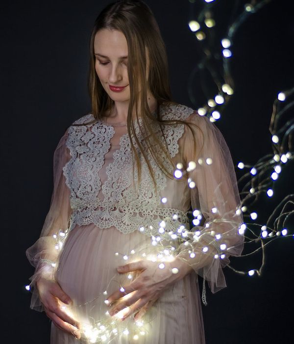 Serene pregnant woman in a gentle yoga pose in a calm studio.